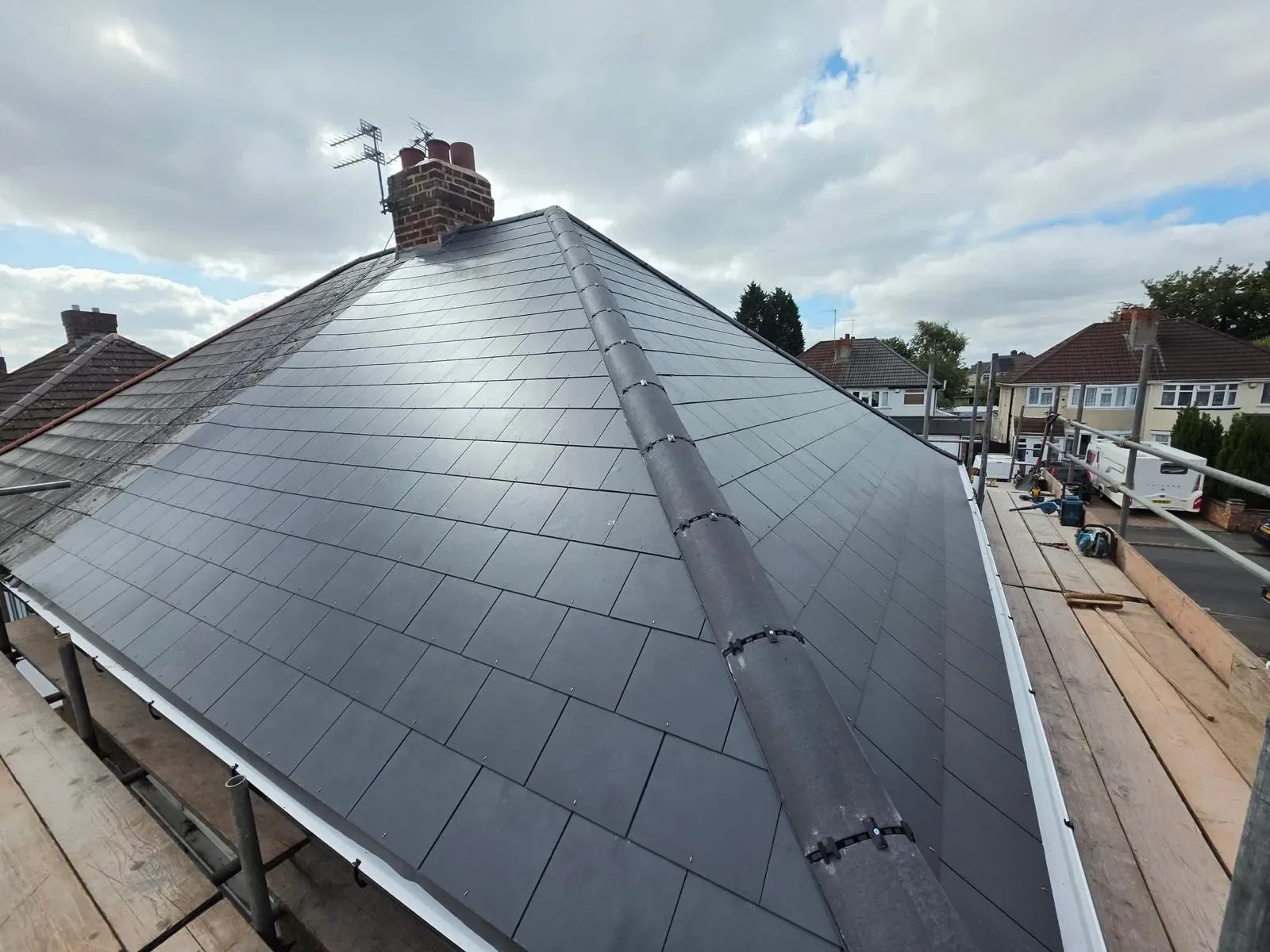 A hipped roof stripped and re-laid in dark concrete tile